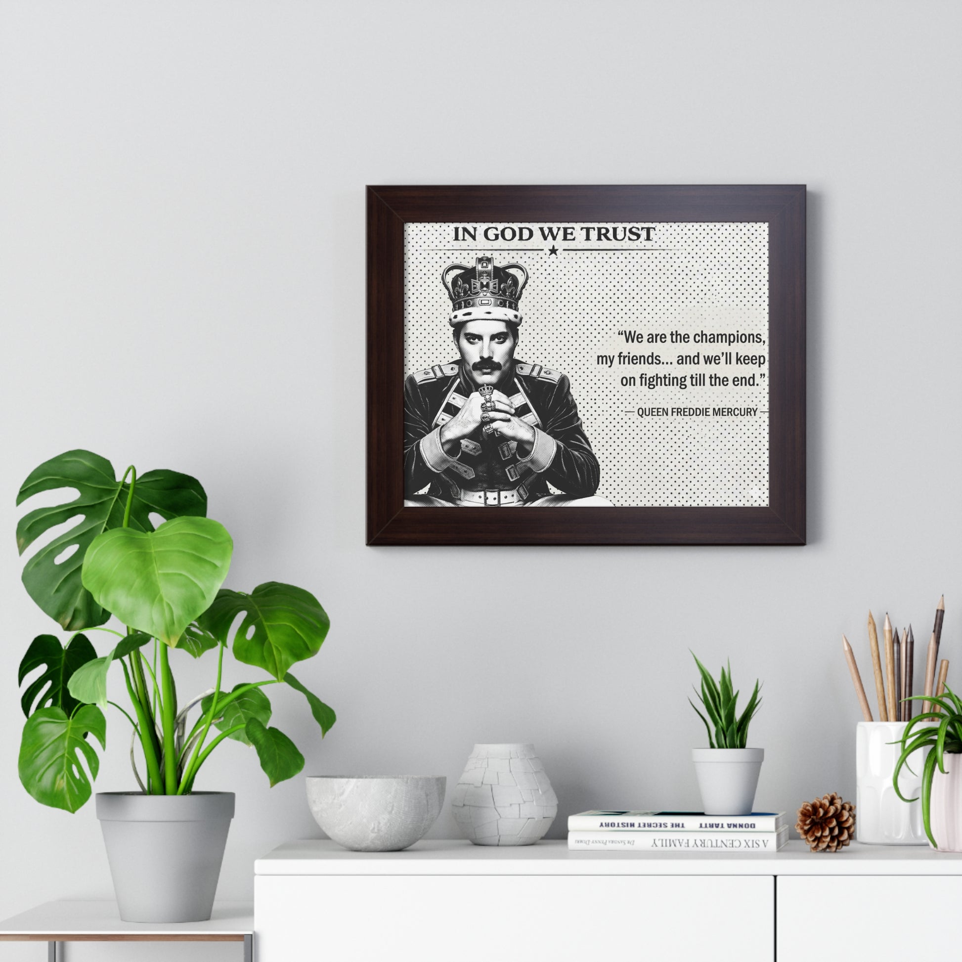 Framed poster with a quote and portrait of a person, placed on a wall above a white cabinet with decorative items.