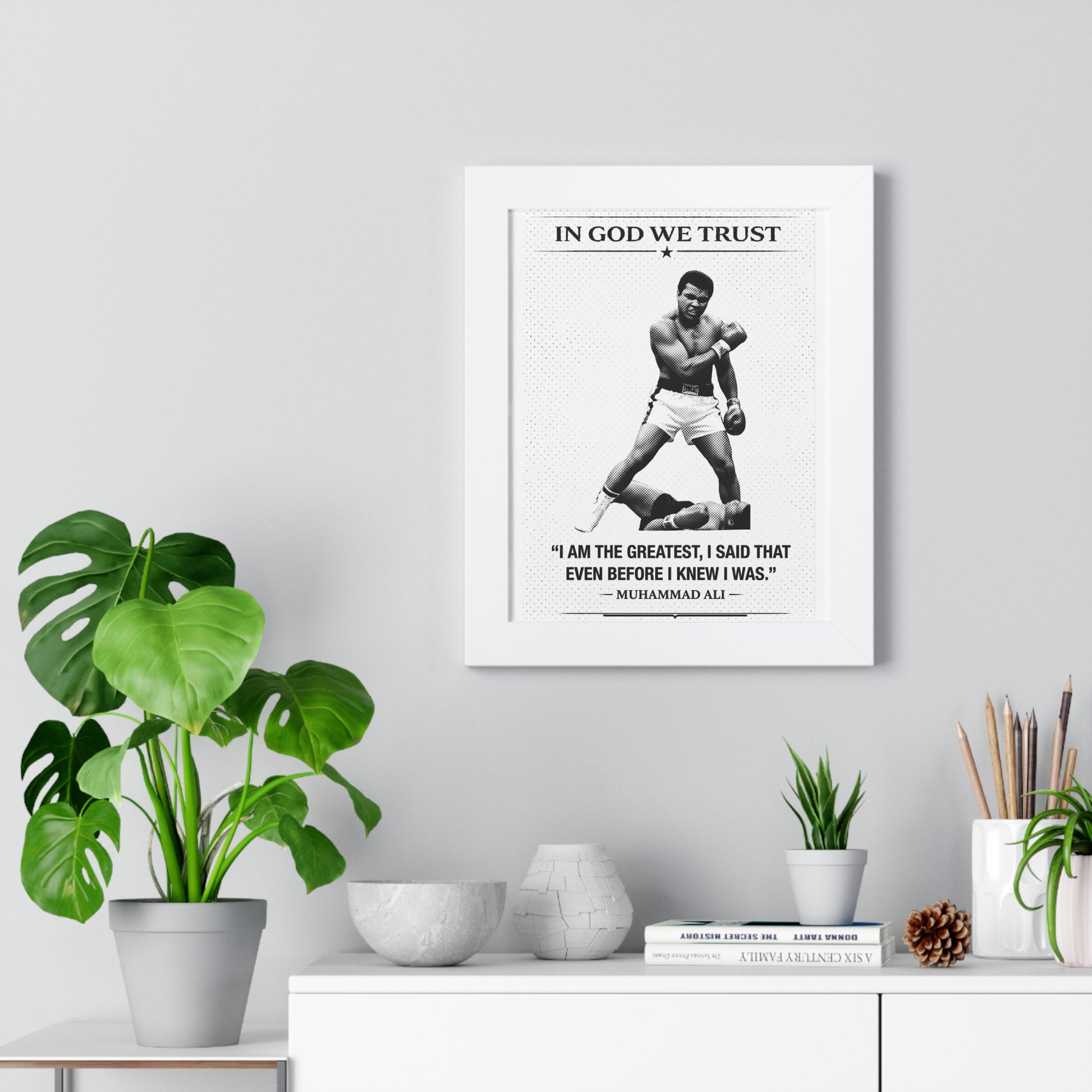 Muhammad Ali poster with quote on a wall above a desk with plants and decor.