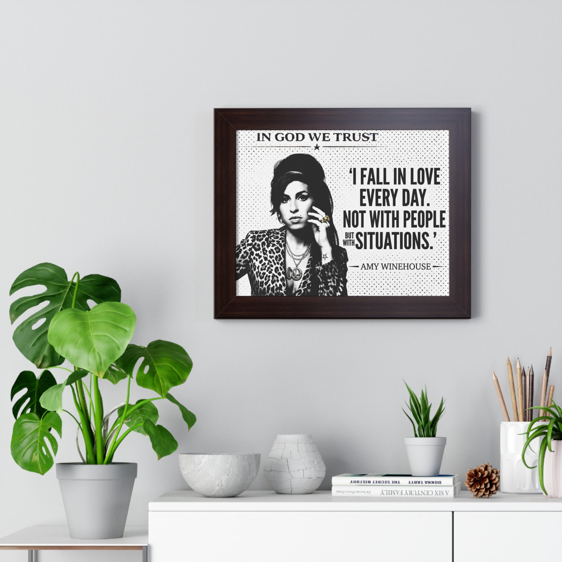 Framed quote by Amy Winehouse on a wall with decorative plants and items.