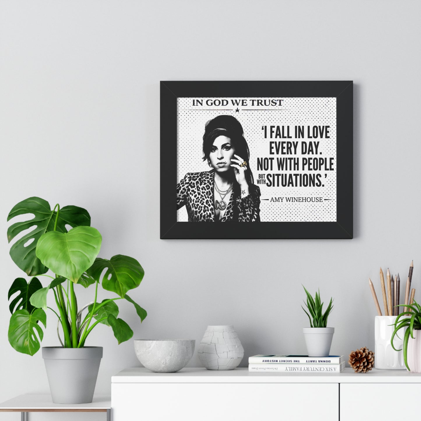 Framed quote by Amy Winehouse on a wall with decorative plants and items.