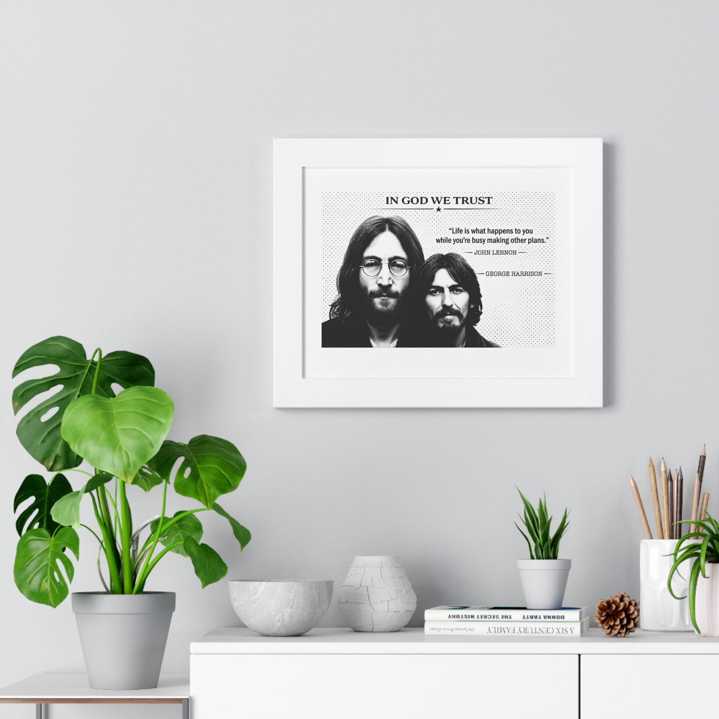 Framed poster with two individuals' faces and text above a desk with plants and decor items.