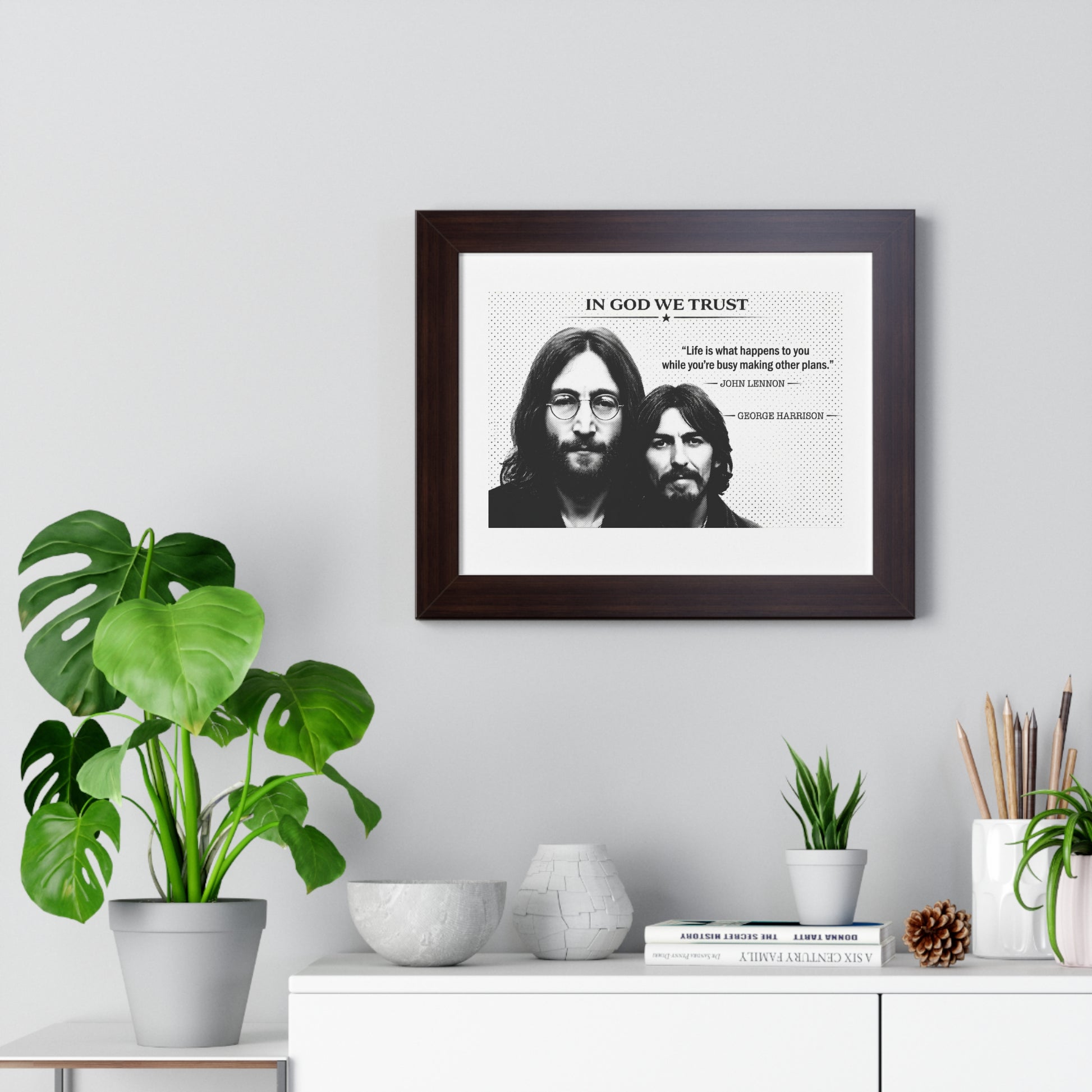 Framed artwork with two individuals and text on a wall above a white cabinet with decorative items.