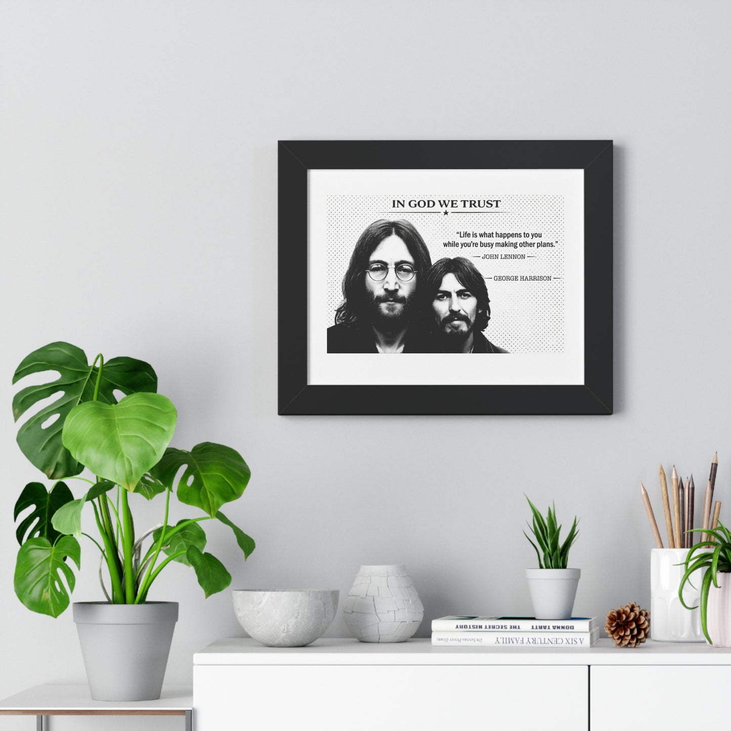 Framed artwork with two individuals' faces and text on a wall with decorative items below.