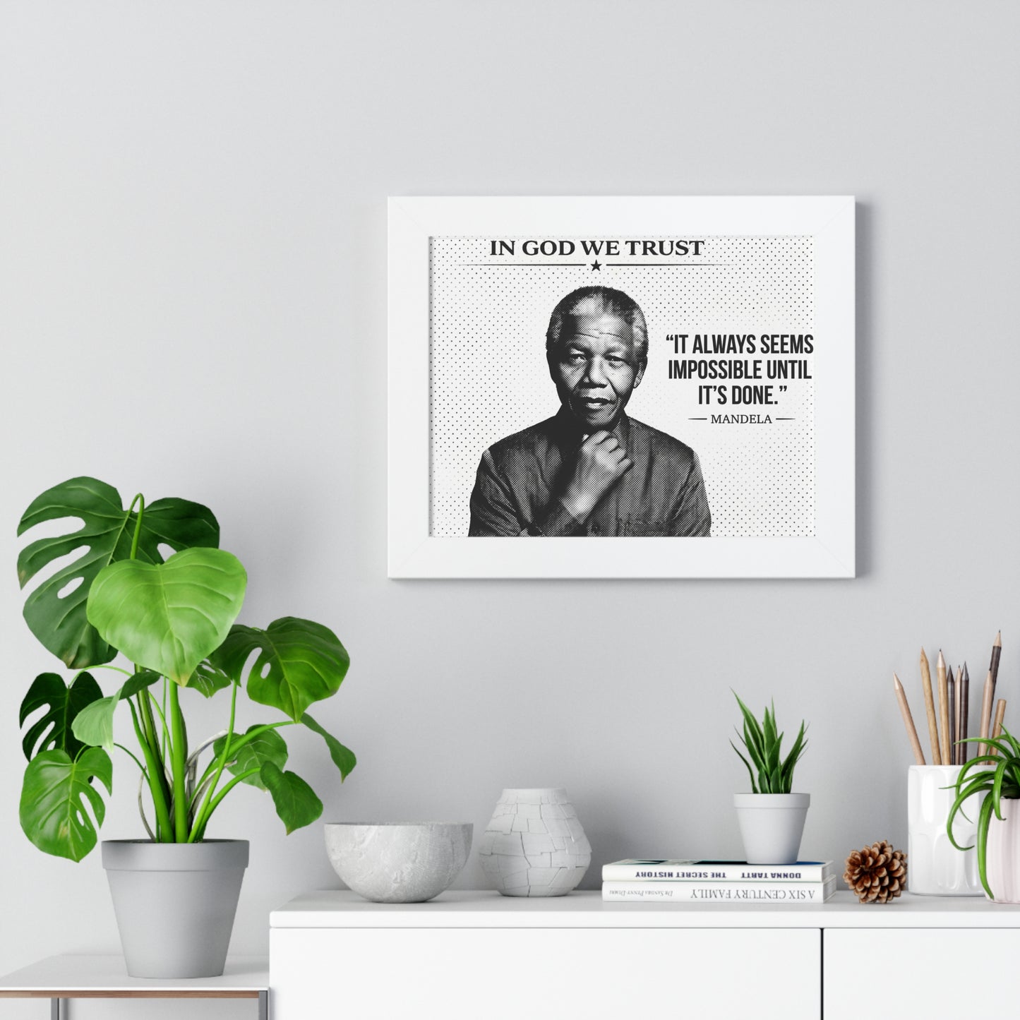 Framed poster with a quote and portrait of a person, placed on a shelf with decorative items.