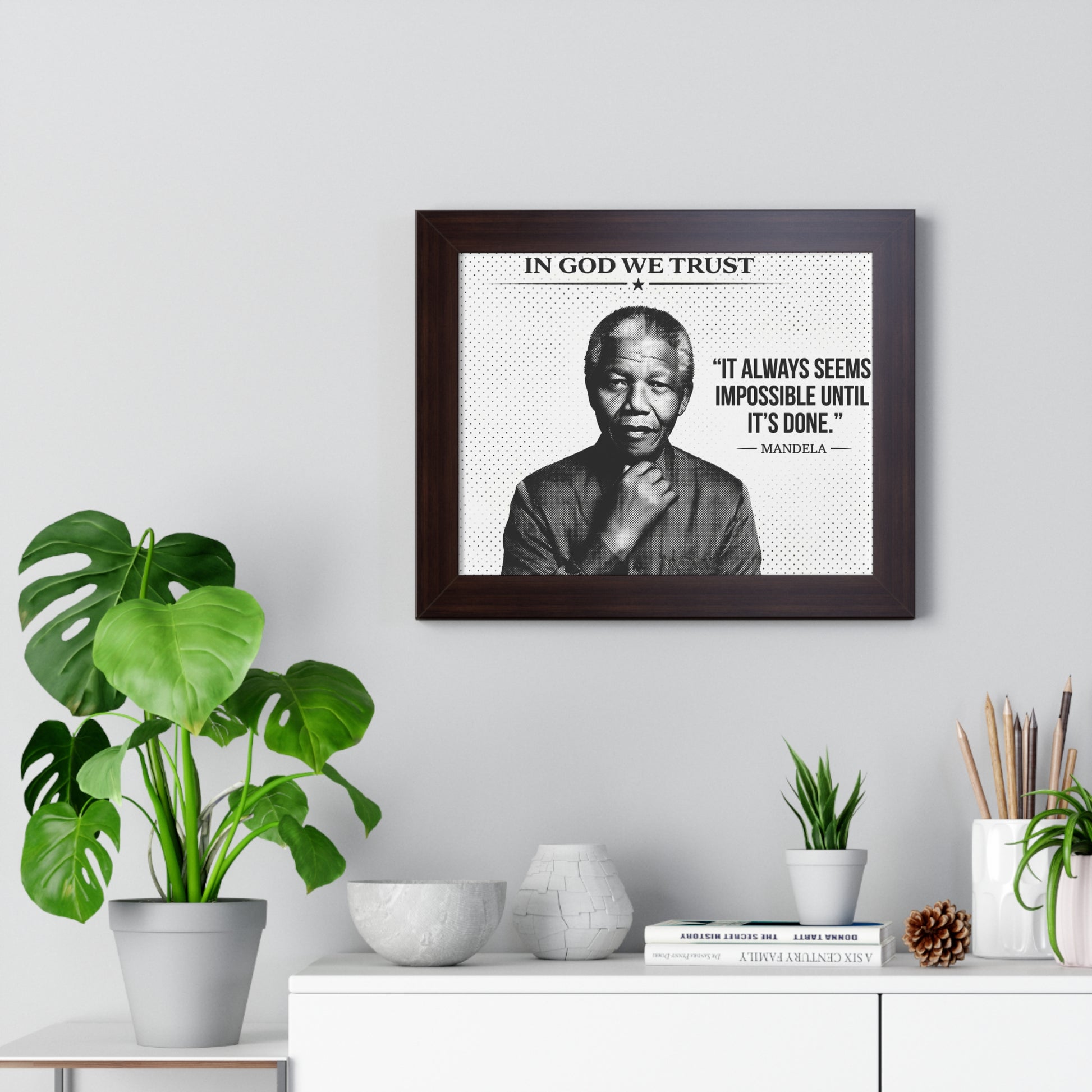 Framed poster with a quote by Nelson Mandela on a wall with decorative plants and items.