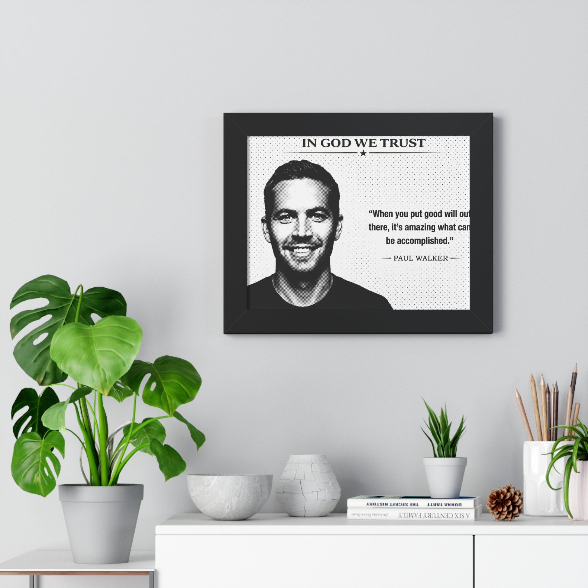 Framed poster with a quote by Paul Walker on a wall above a white cabinet with decorative items.