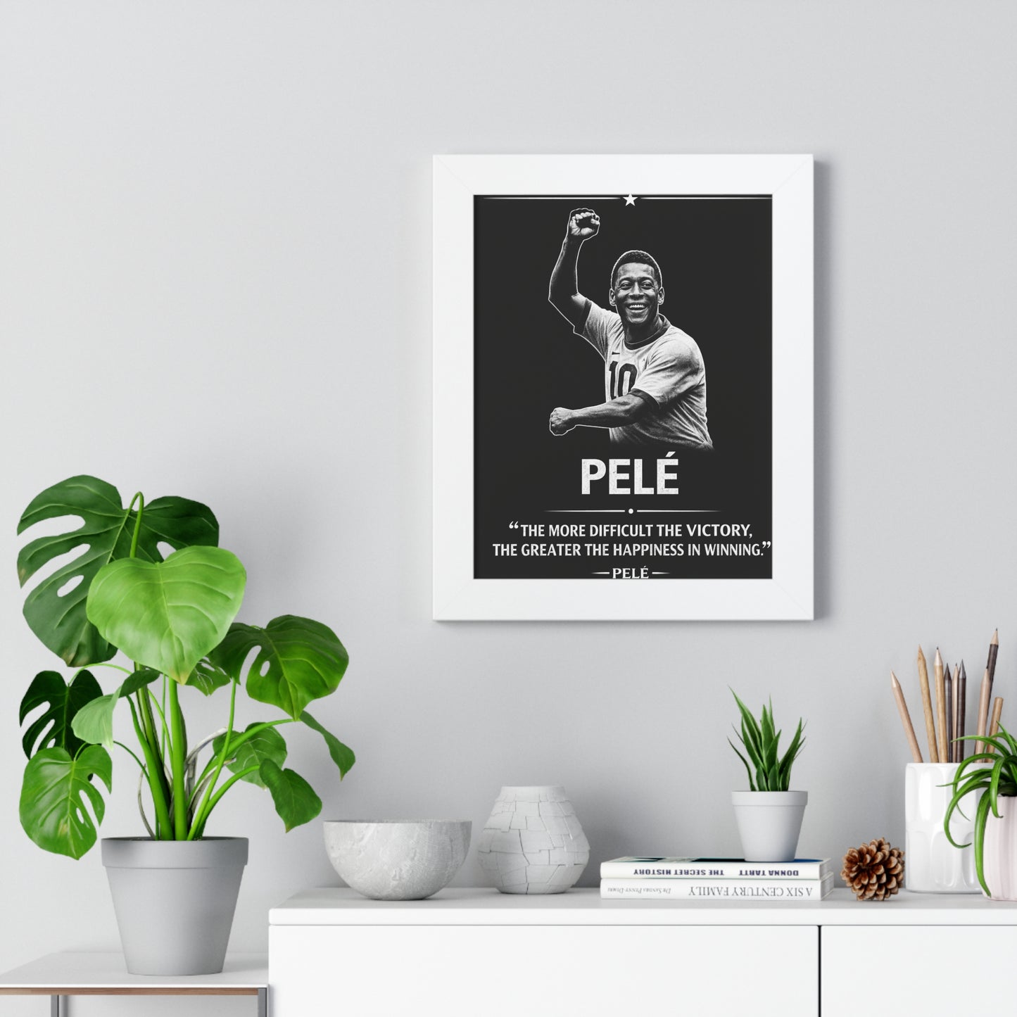 Framed Pelé poster on a wall with decorative items below.