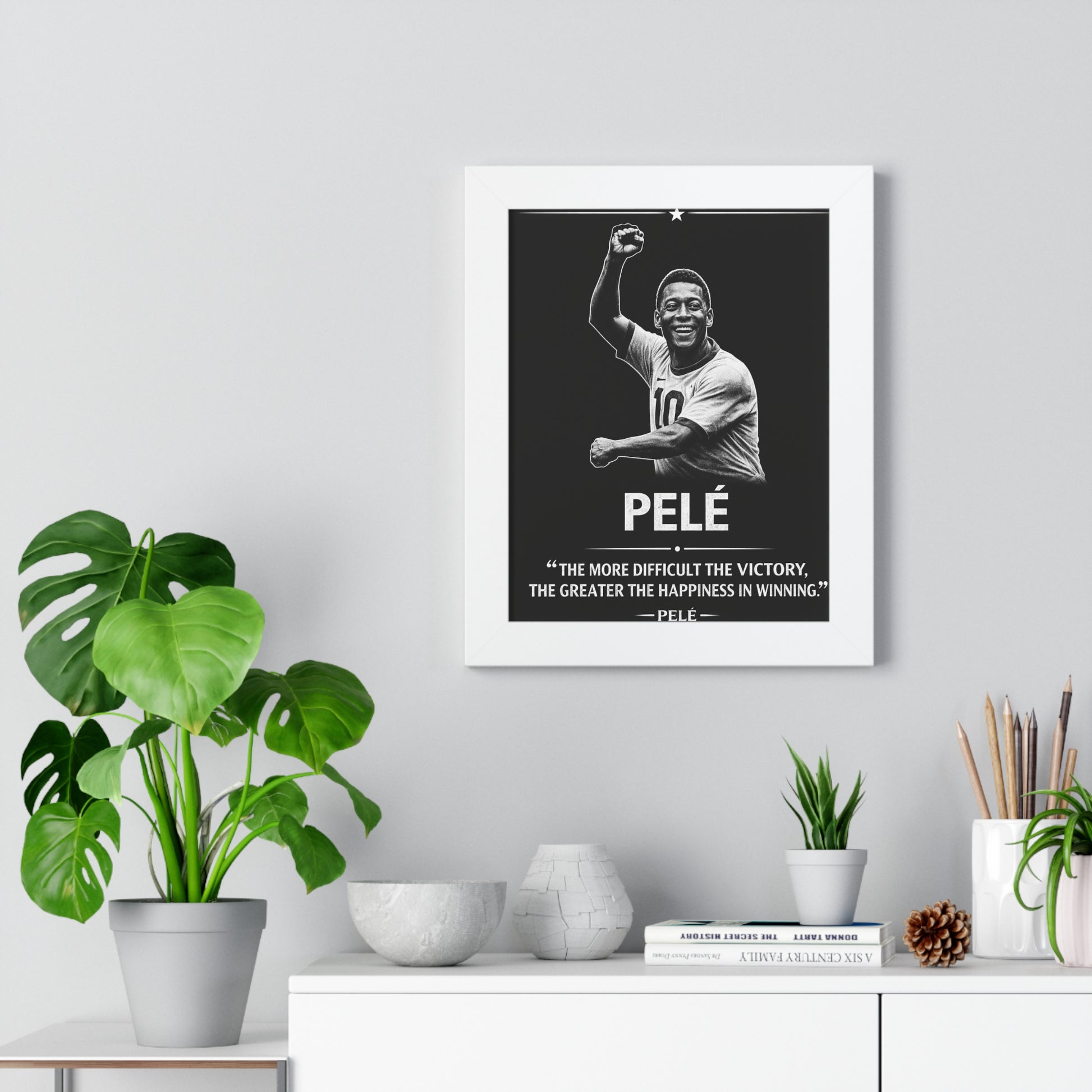 Framed Pelé poster on a wall with decorative items below.