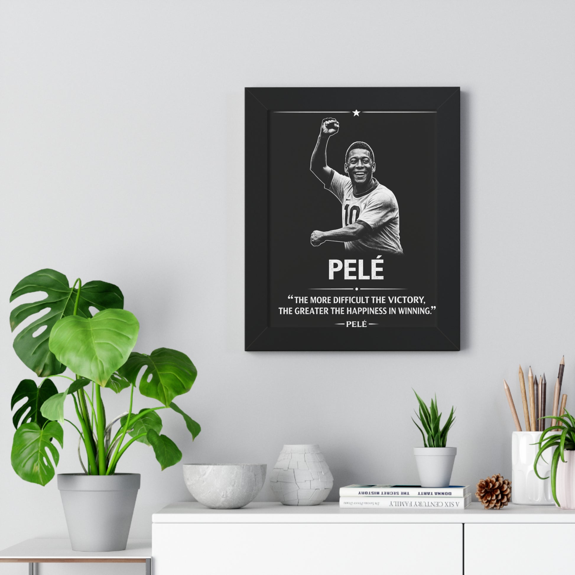 Framed Pelé poster on a wall with decorative items below.