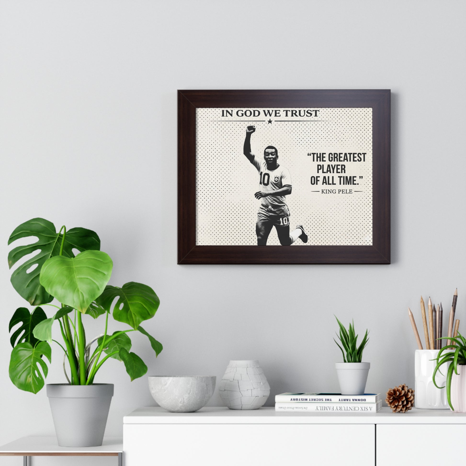 Framed poster with a sports player and text on a wall above a white cabinet with decorative items.