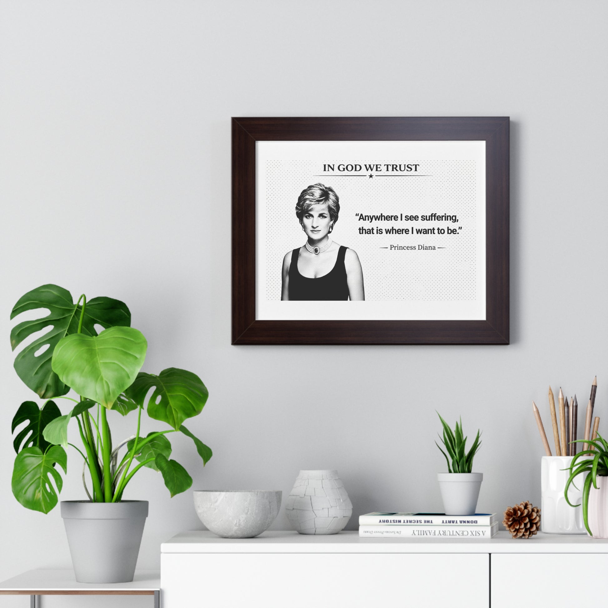 Framed print of Princess Diana with a quote on a wall above a desk with plants and decor items.