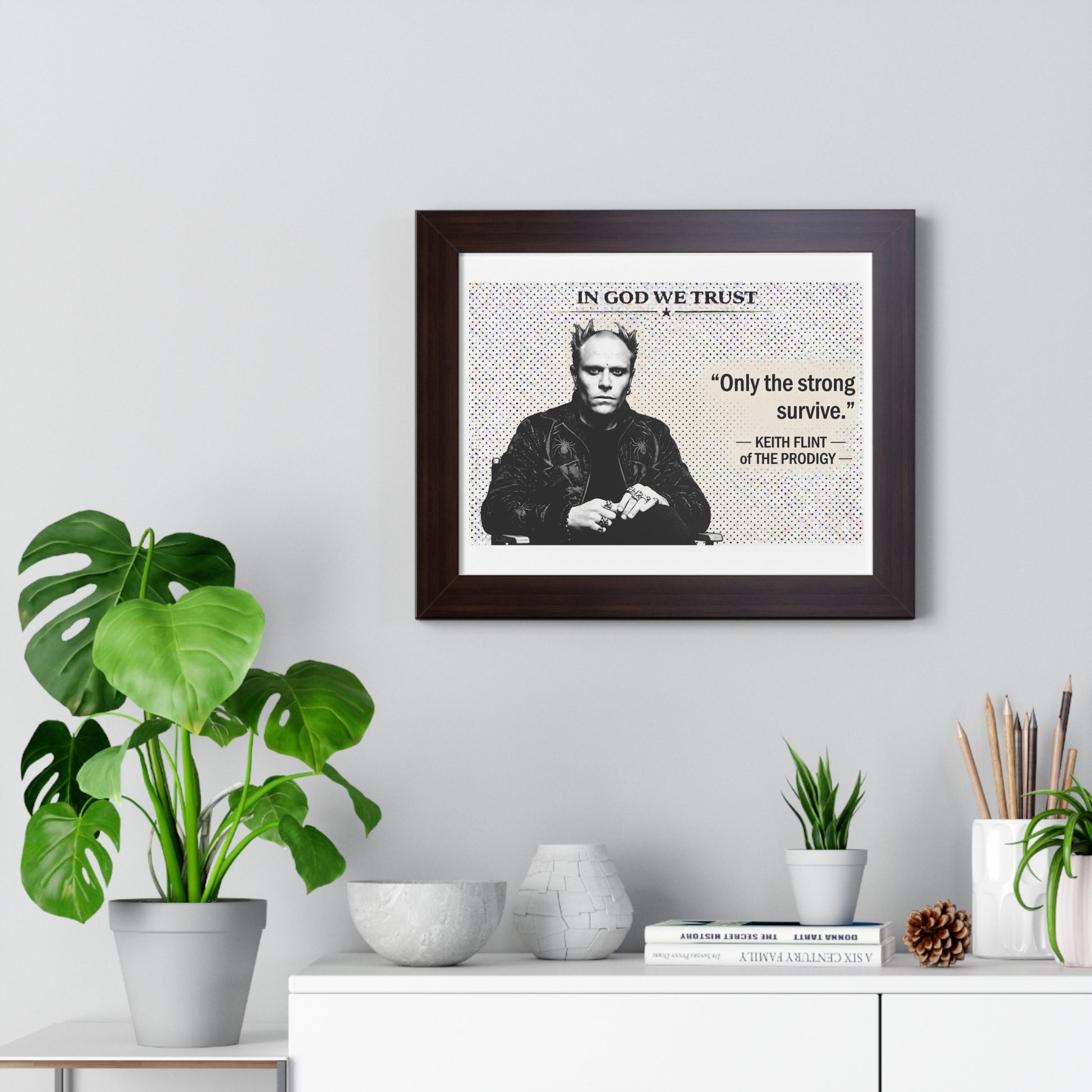 Framed poster with a quote and image of a person on a wall above a white cabinet with decorative items.