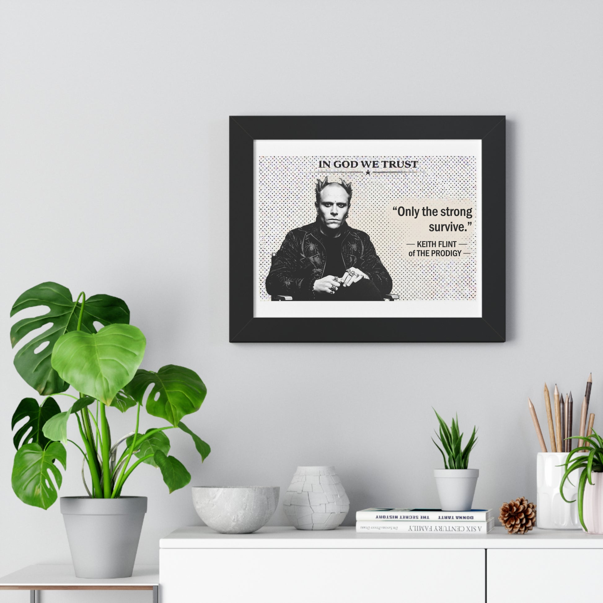 Framed poster with a quote and image of a person on a wall above a white cabinet with decorative items.