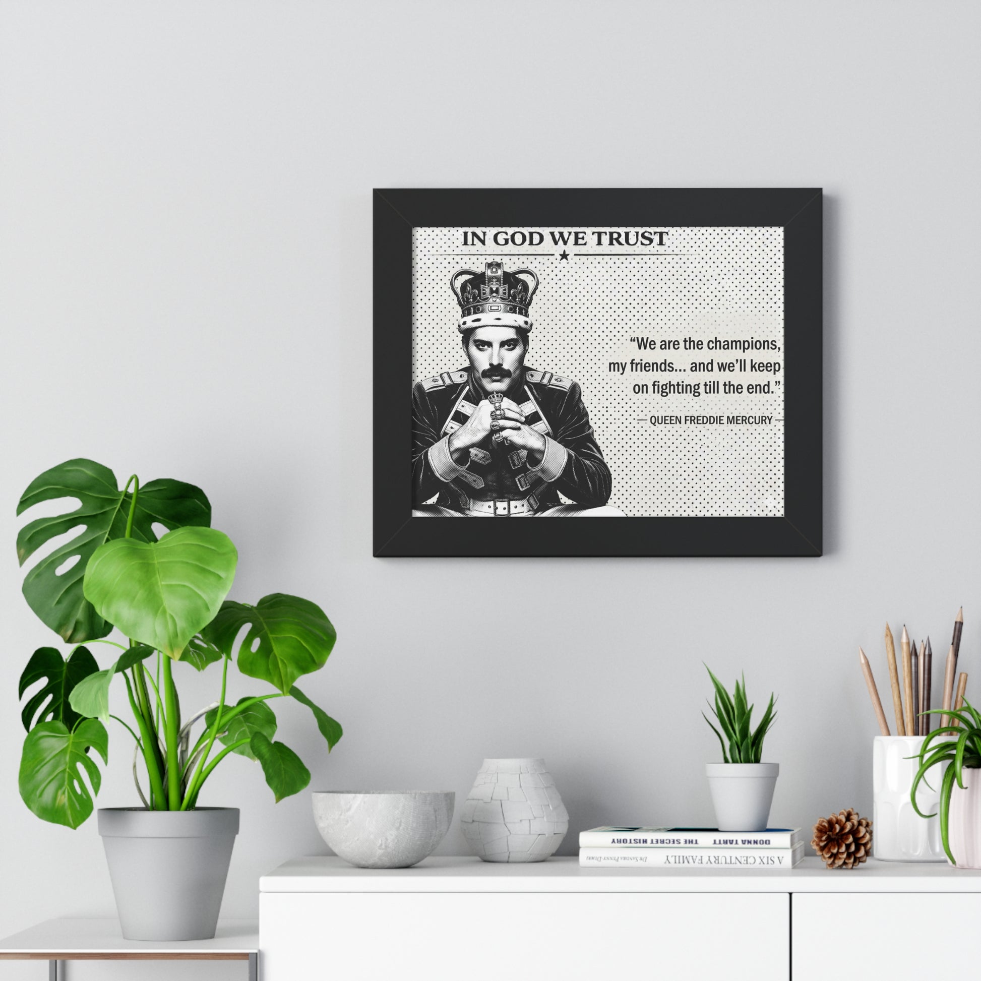 Framed poster with a quote and image of a person, placed on a wall above a white cabinet with decorative items.