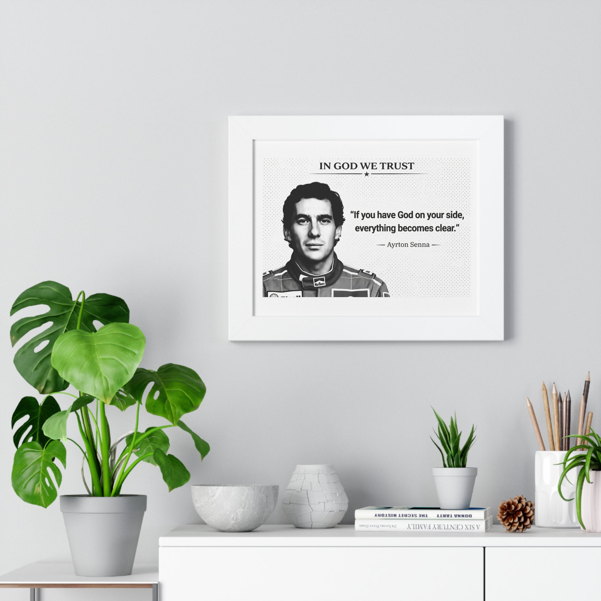 Framed portrait with a quote on a wall above a white cabinet with decorative items.