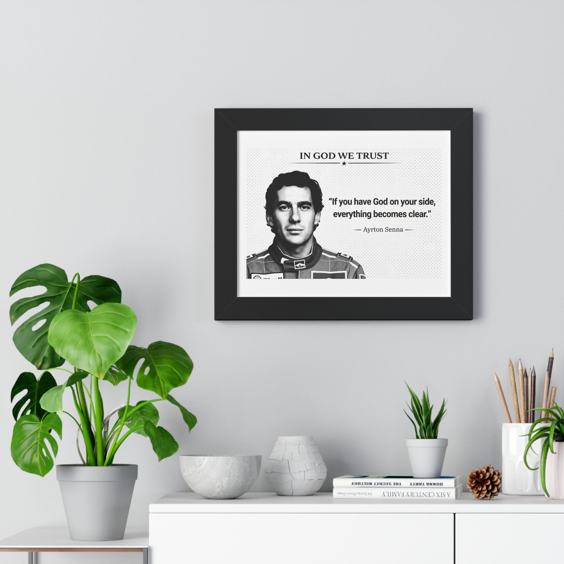 Framed portrait with a quote on a wall above a white cabinet with decorative items.