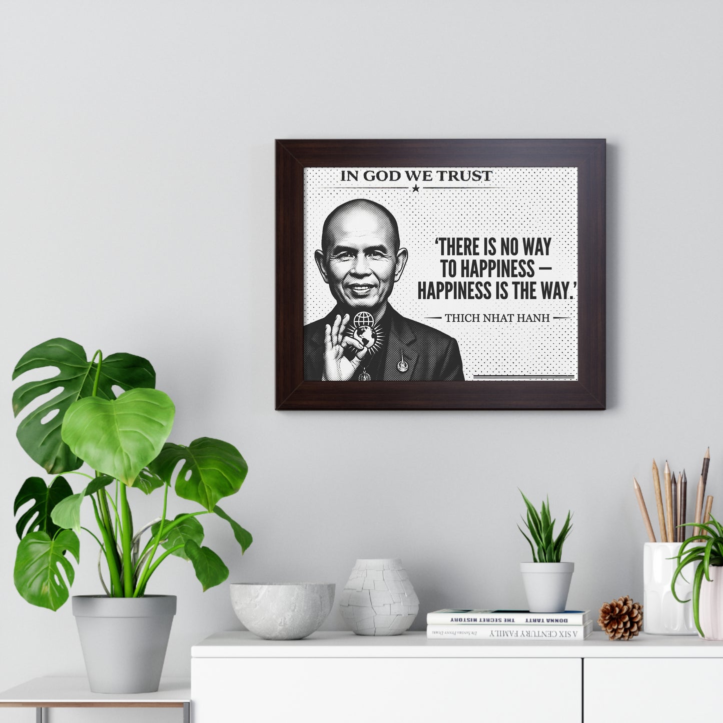 Framed picture of a man with a quote on a wall above a desk with plants and decor.