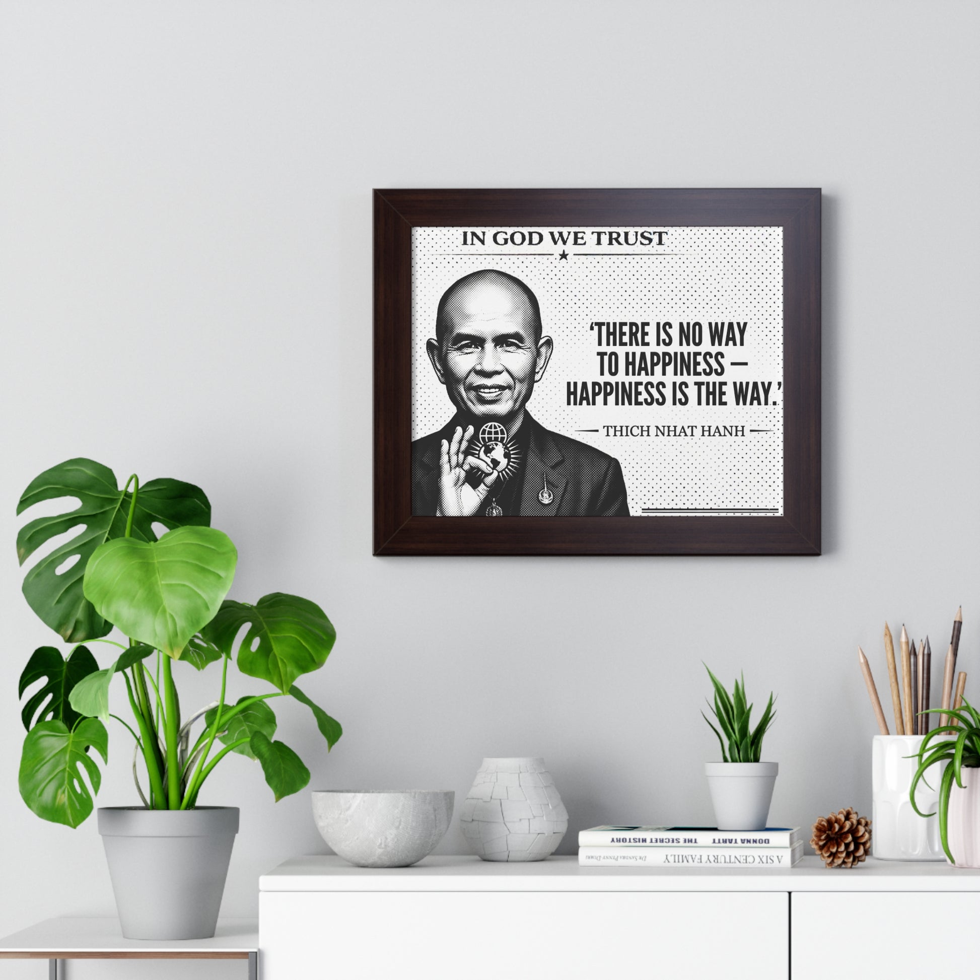Framed picture of a man with a quote on a wall above a desk with plants and decor.