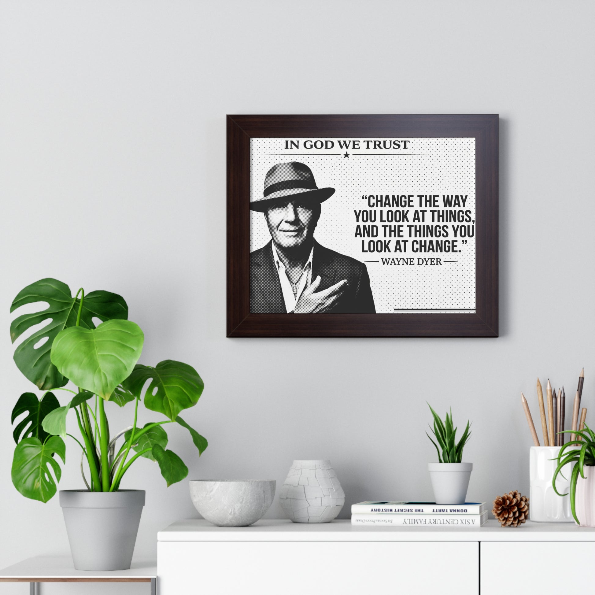 Framed picture of a man with a quote on a wall above a white cabinet with decorative items.
