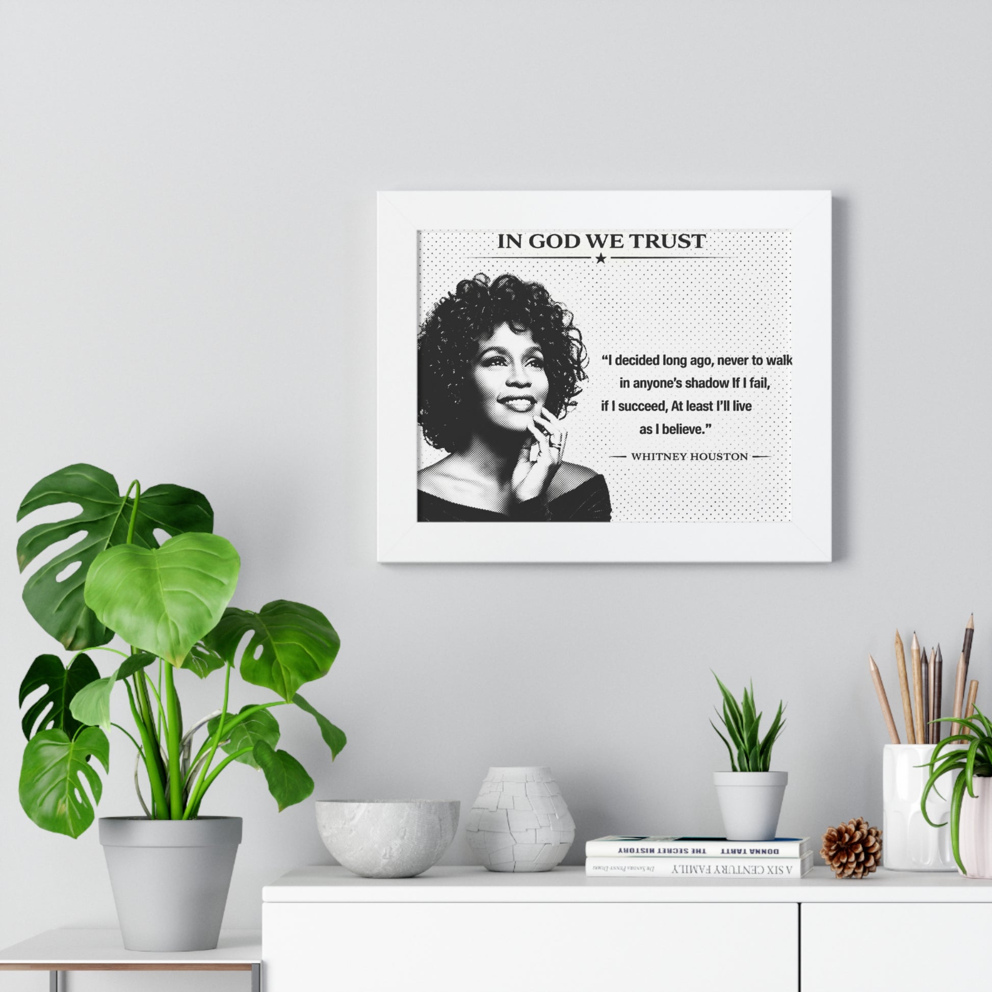 Framed ART of a woman with a quote on a wall above a desk with plants and decor items.