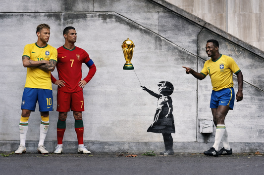 Three soccer players in different uniforms standing next to a Banksy-style mural of a girl with a World Cup trophy.