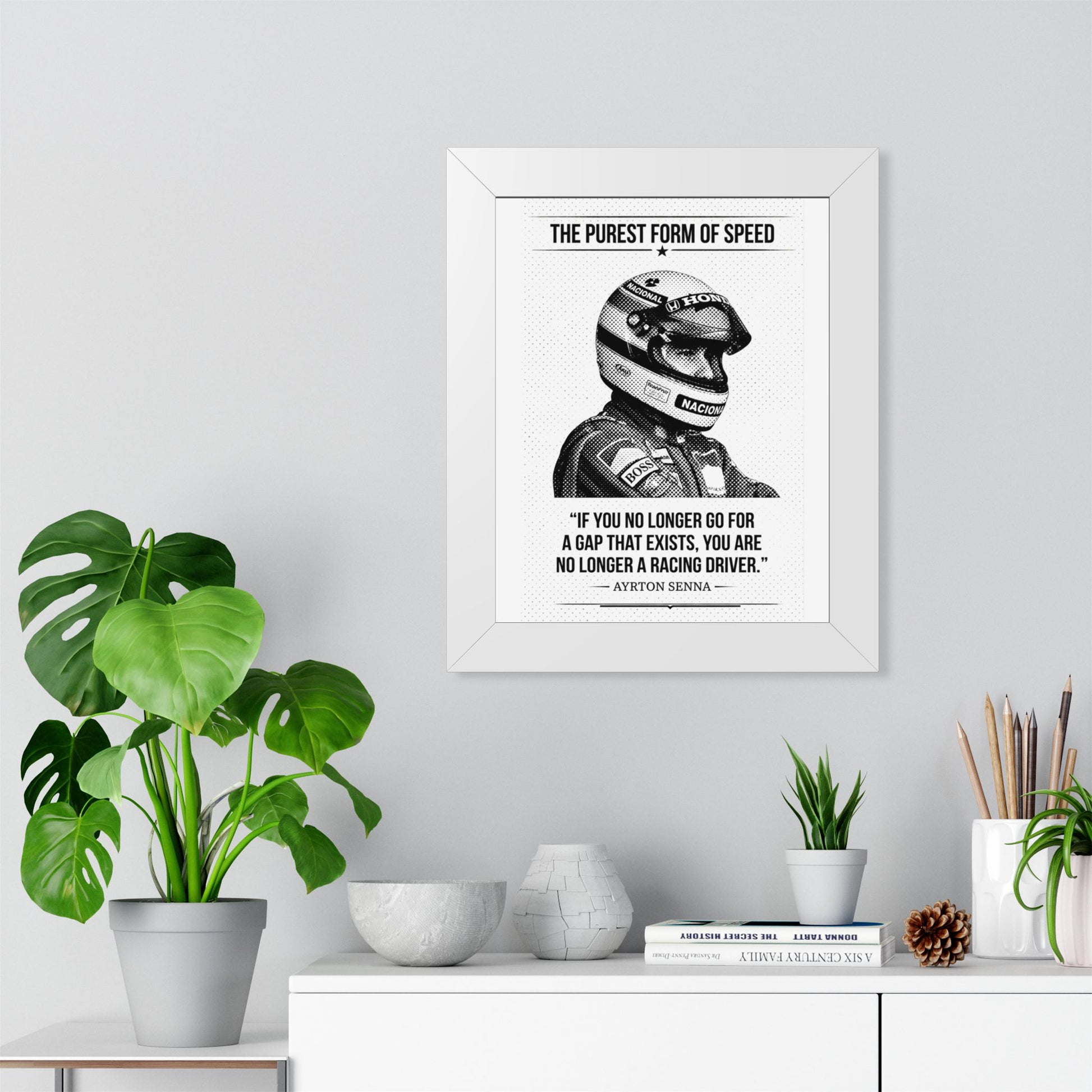 Framed ART with Ayrton Senna's quote on a wall above a desk with plants and decor items.