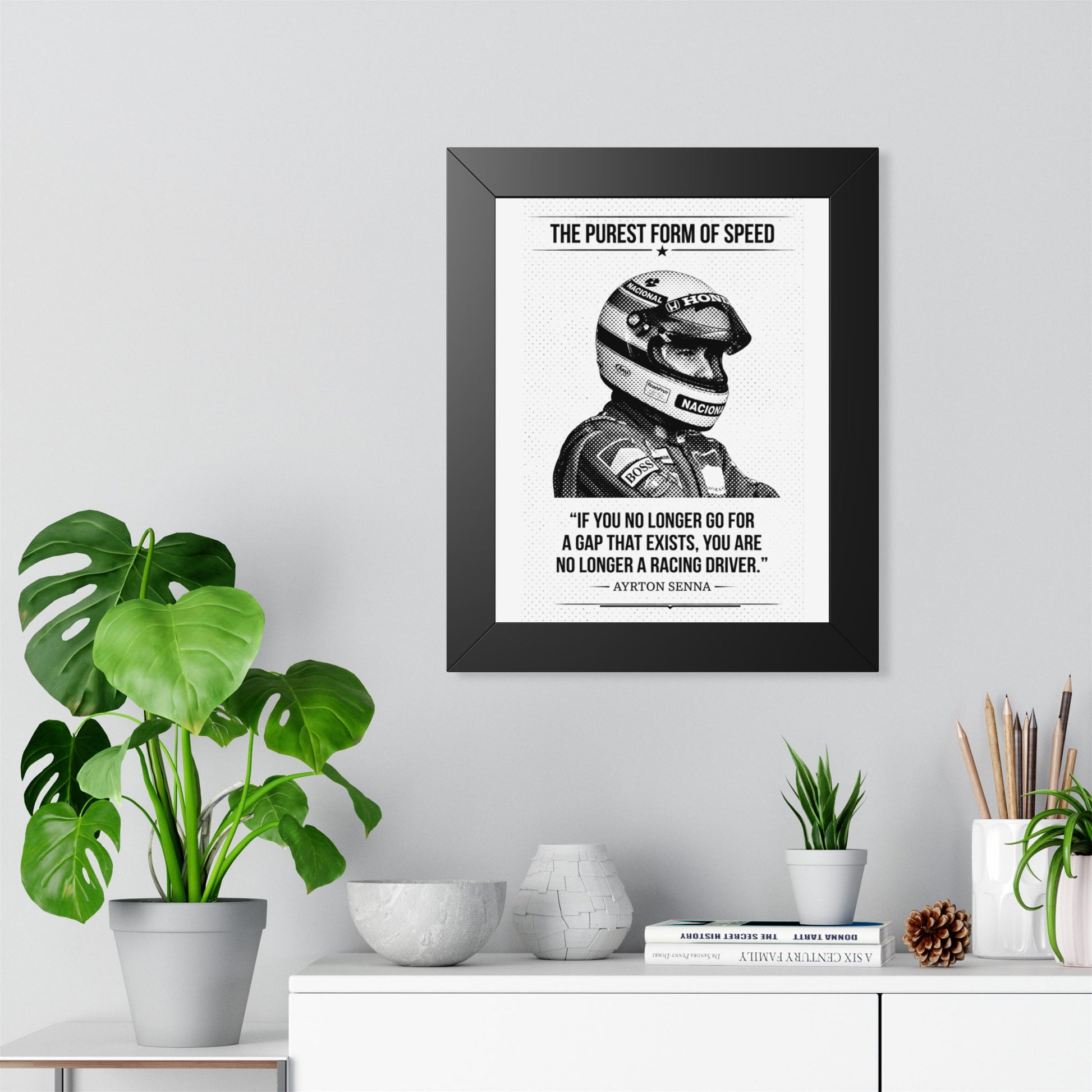 Framed ART with Ayrton Senna's quote on a wall above a desk with plants and decor.