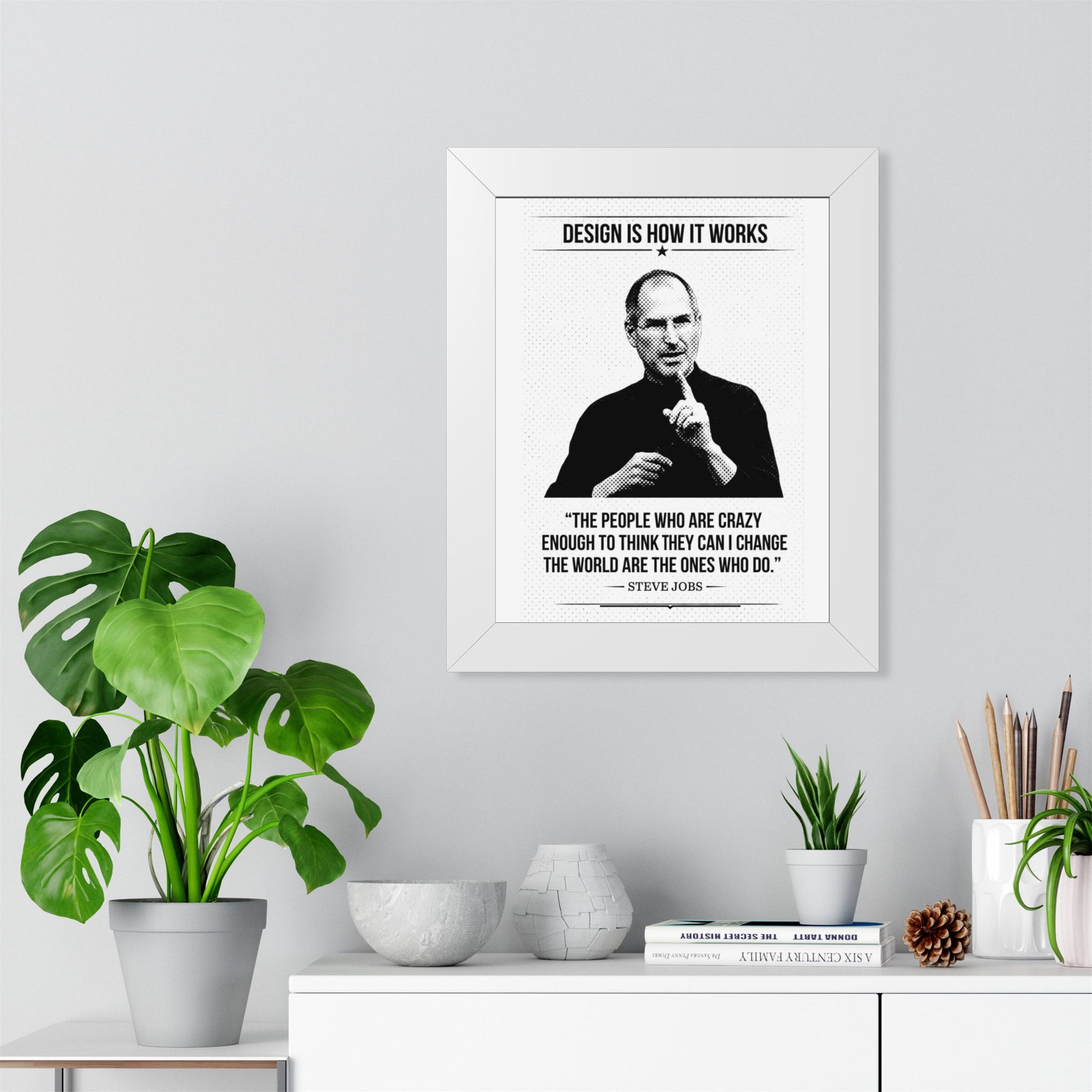 Framed Steve Jobs quote on a wall with plants and decor below